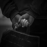 a black and white photo of a person holding a handbag